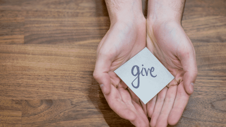 open hands with a sticky note that says give
